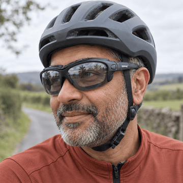 Cyclist in rust jersey wearing Eyesnug sunglasses outdoors.